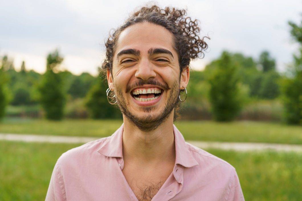 Joyful Young Man with Curly Hair Laughing in Park