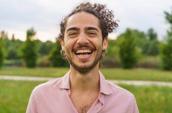 Joyful Young Man with Curly Hair Laughing in Park